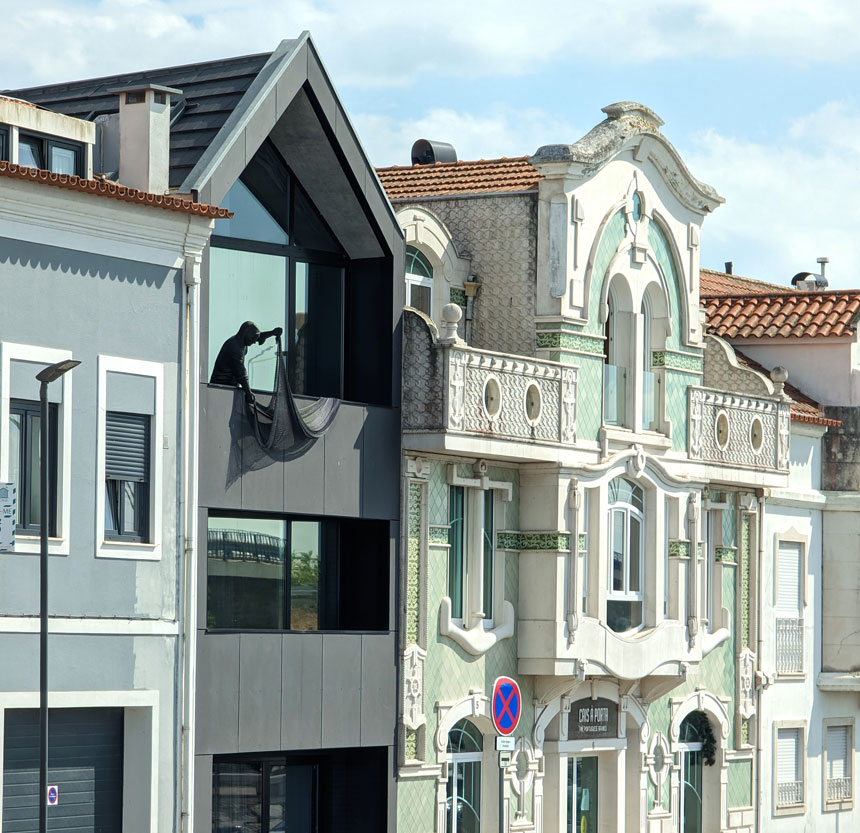 This modern house has a sculpture of a fisherman on its balcony