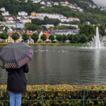 A woman standing with her back to the camera, holding an umbrella on a rainy day in Bergen