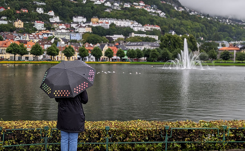 A woman standing with her back to the camera, holding an umbrella on a rainy day in Bergen