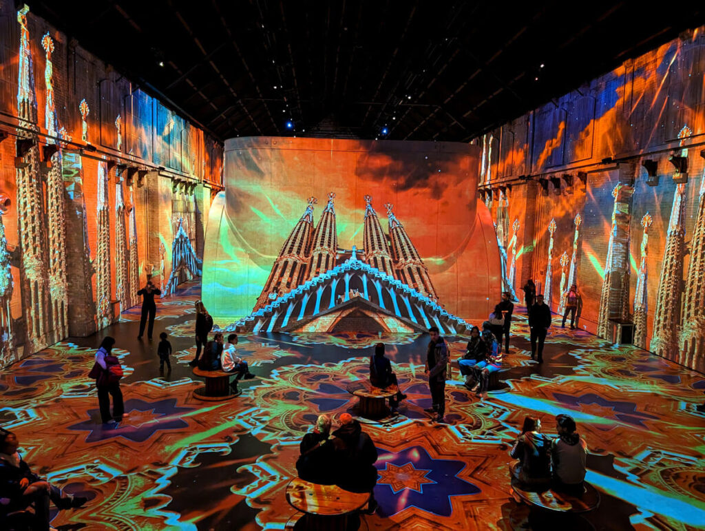 The Gaudì immersive experience at Fabrique des Lumières. A massive industrial space is filled with a colourful, moving projection of the Sagrada Familia cathedral.