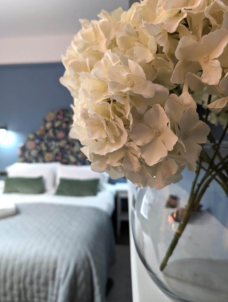 Flowers on the mantlepiece at Arlington House Hotel, with the bed in the background