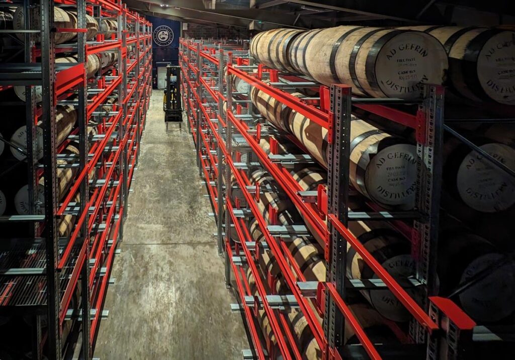Whisky barrels piled high on metal racks in Ad Gefrin's bonded warehouse