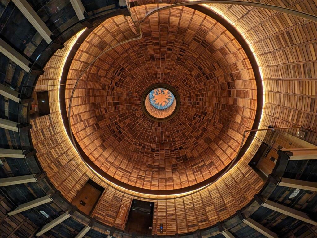 Looking up in the entrance hall. A circular staircase rises up the wooden walls.