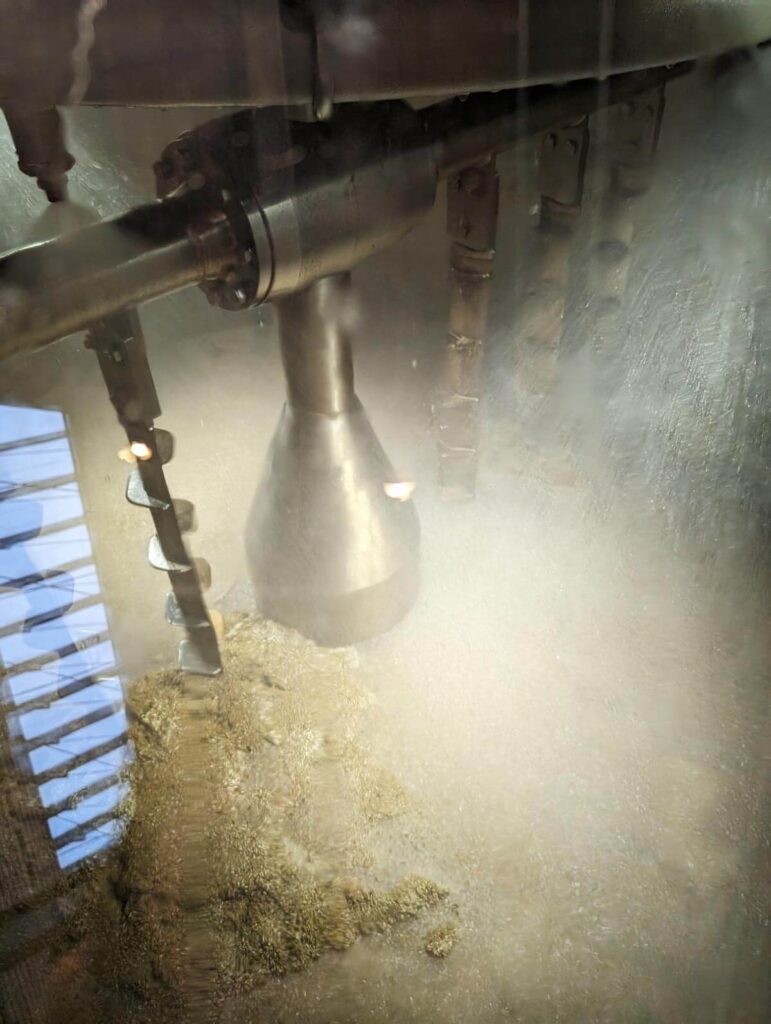 Barley being mixed with water in a giant vat. The barley at the bottom looks like porridge.