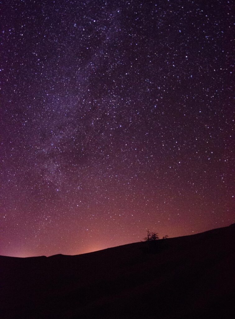 The night sky full of stars in the Moroccan desert, with the shadow of a sand dune in the foreground