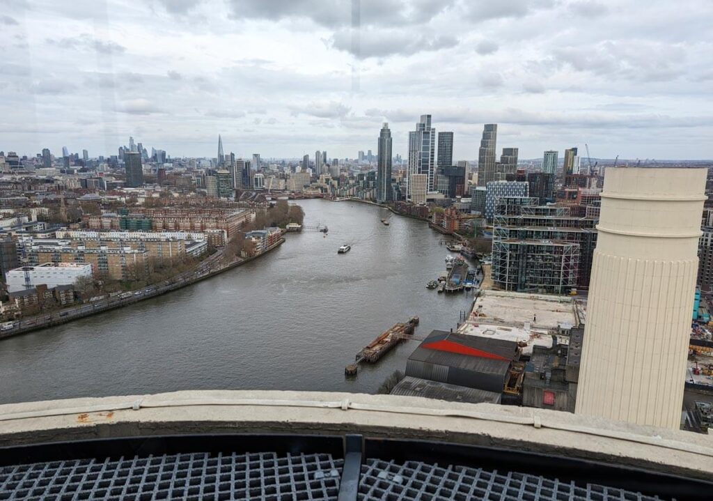 The view from Lift 109 at Battersea Power Station. You can see another one of the power station's four chimneys in the foreground, along with the River Thames and the skyscrapers of the City of London in the background.