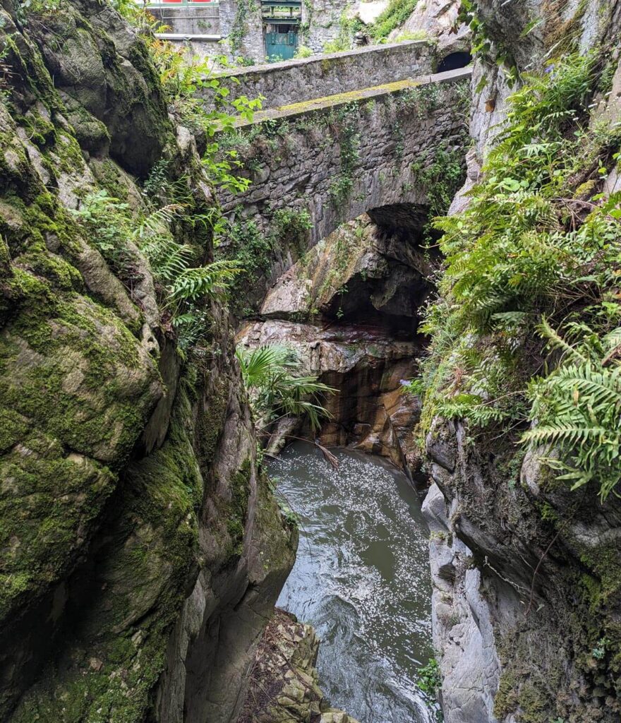 A small, old stone bridge crossing a fiercely flowing stream