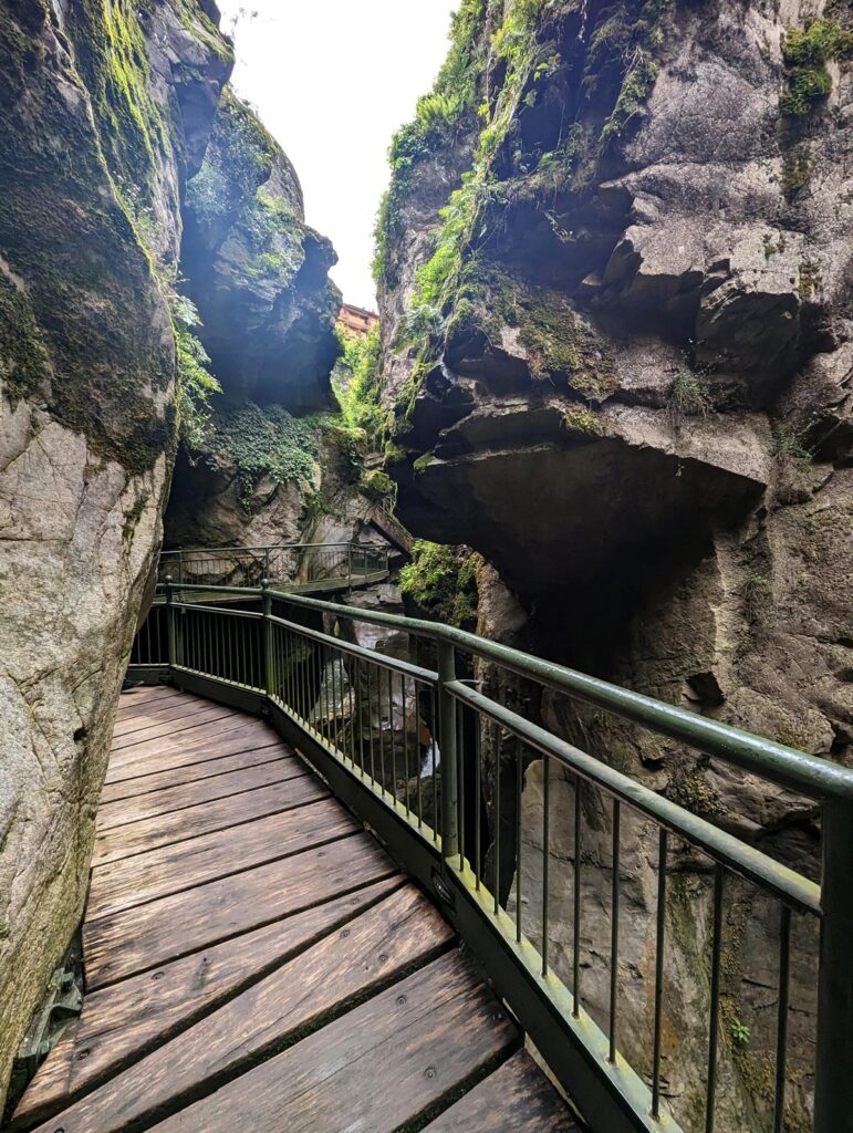 A narrow rocky ravine, with a wooden walkway suspended on one side