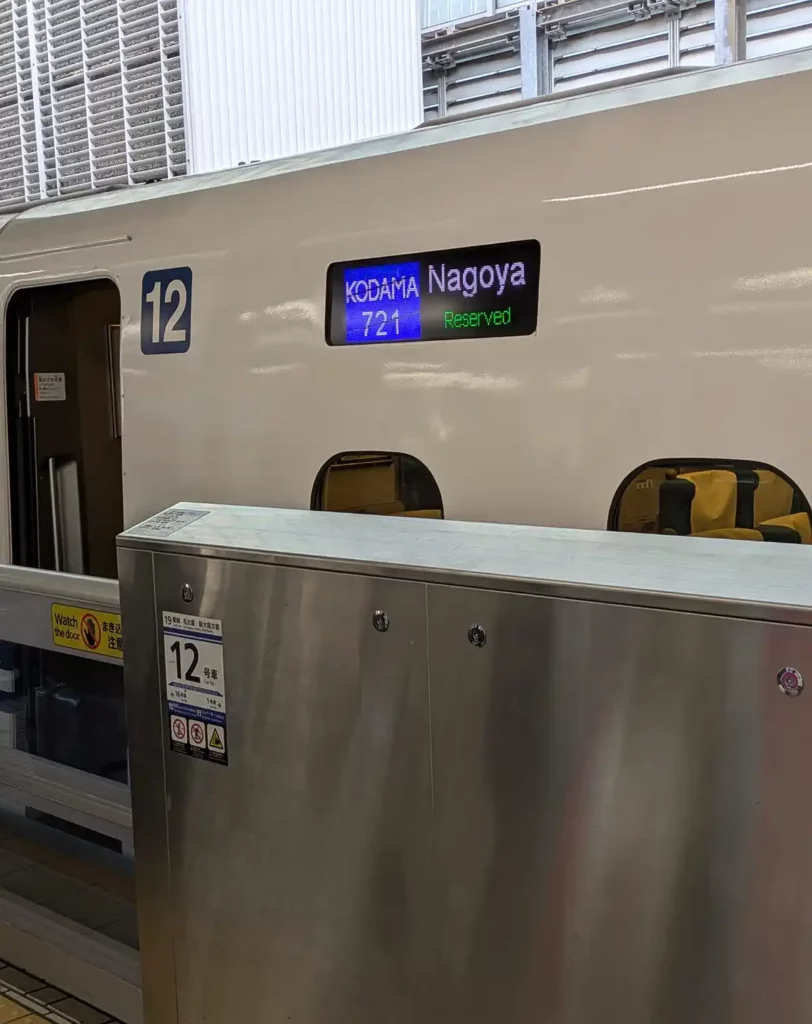 A Shinkhansen train at Tokyo Station, showing the train's destination (Nagoya) and the train name and number (Kodama 721) on the coach display