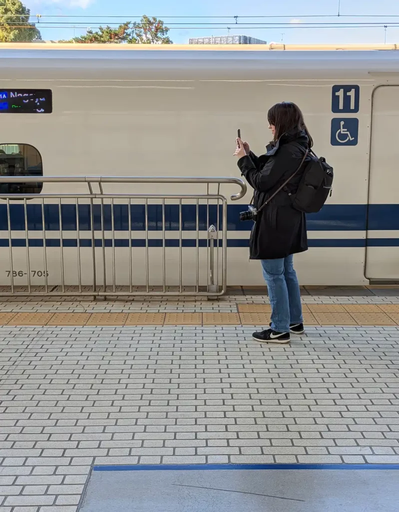 A woman (me!) filming the Shinkansen departing at Odawara