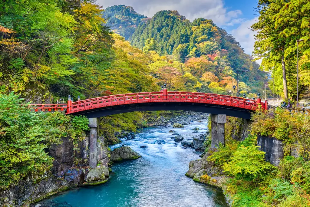 A red bridge crossing a beautiful river valley in Nikko, Japan