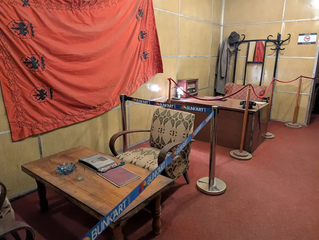 Enver Hoxha's office at Bunk'Art 1. There is a desk and seating area, with a large Albanian flag on the wall.