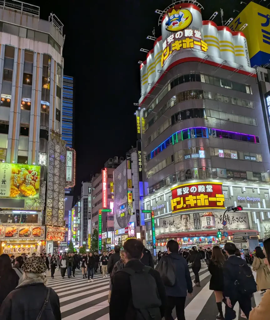 A Don Quijote store in Shinjuku, Tokyo, with a brightly-lit facade and the shop's mascot of a penguin on the top of the building