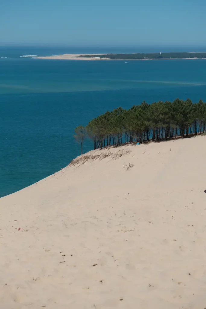 Looking out towards Cap Ferret across Arcachon bay. The huge Dune du Pilat is sloping away from the camera in the foreground, then there's a bay. In the background you can just see another narrow, curving sandbank , the Cap Ferret peninsula.