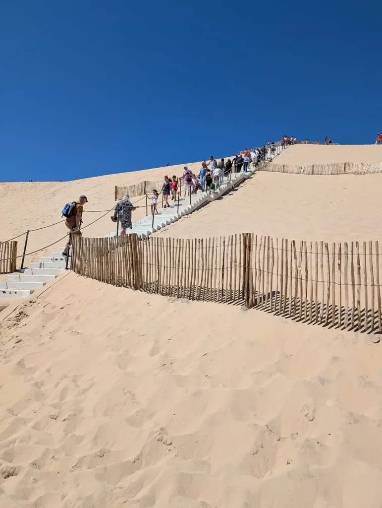 People walking up temporary steps on a huge sand dune