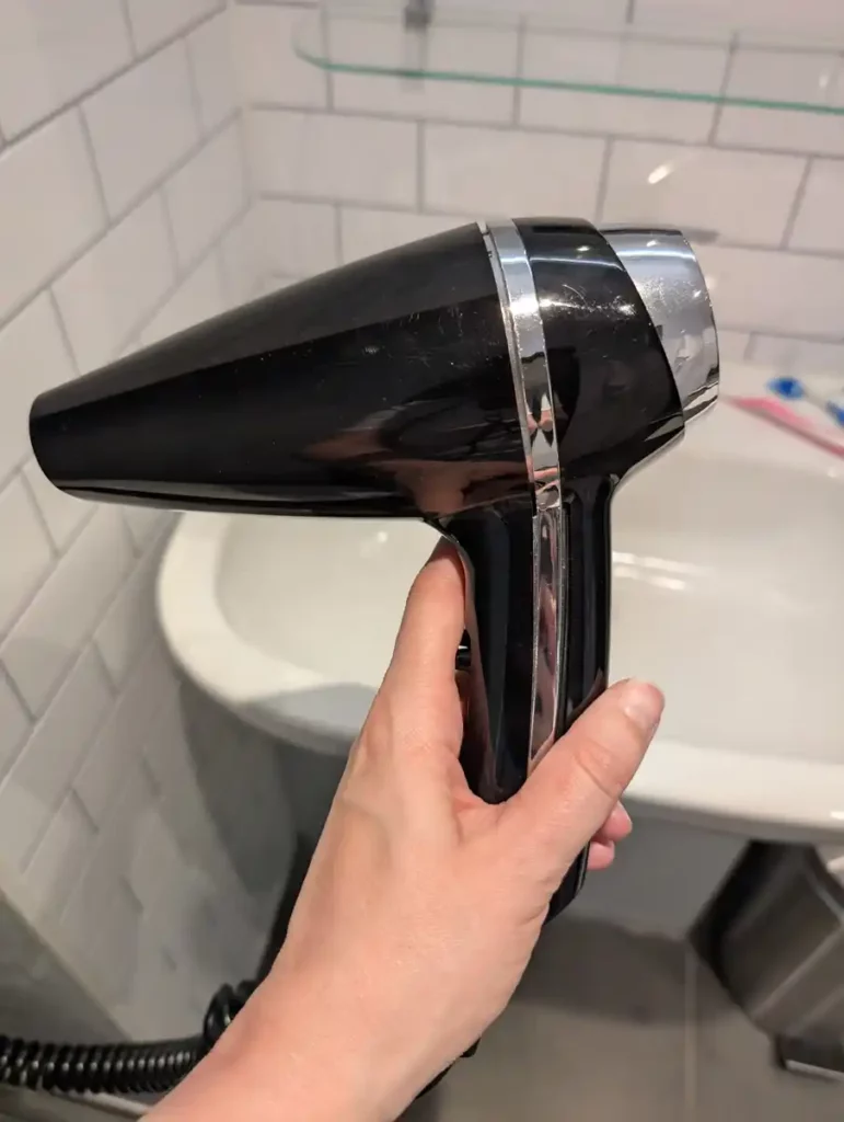 A woman's hand holding a hotel hairdryer