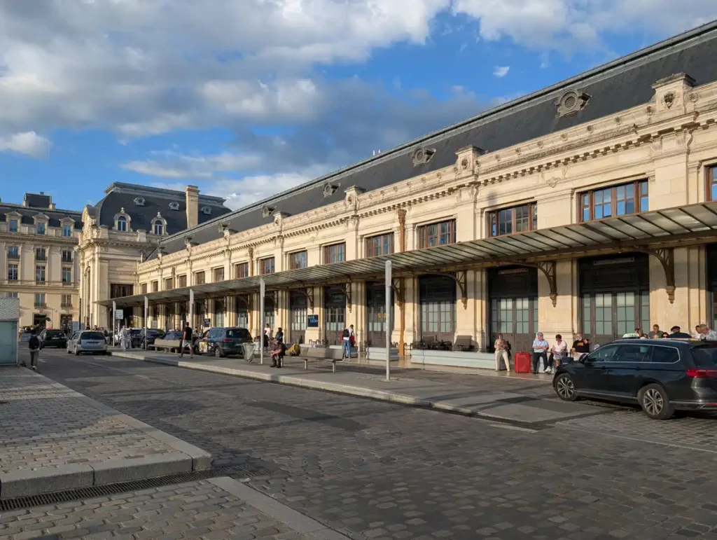 A large 19th century stone railway station, with taxis waiting outside