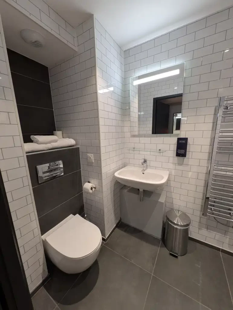 A hotel bathroom, decorated in white and grey