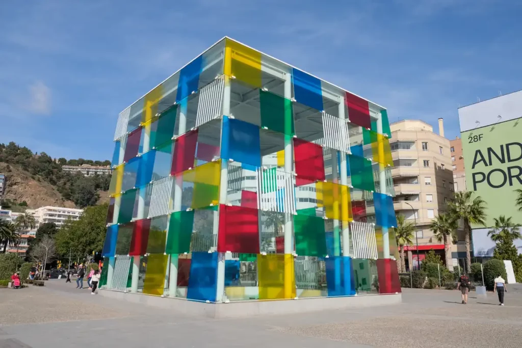 A glass cube building with a patchwork of coloured panels