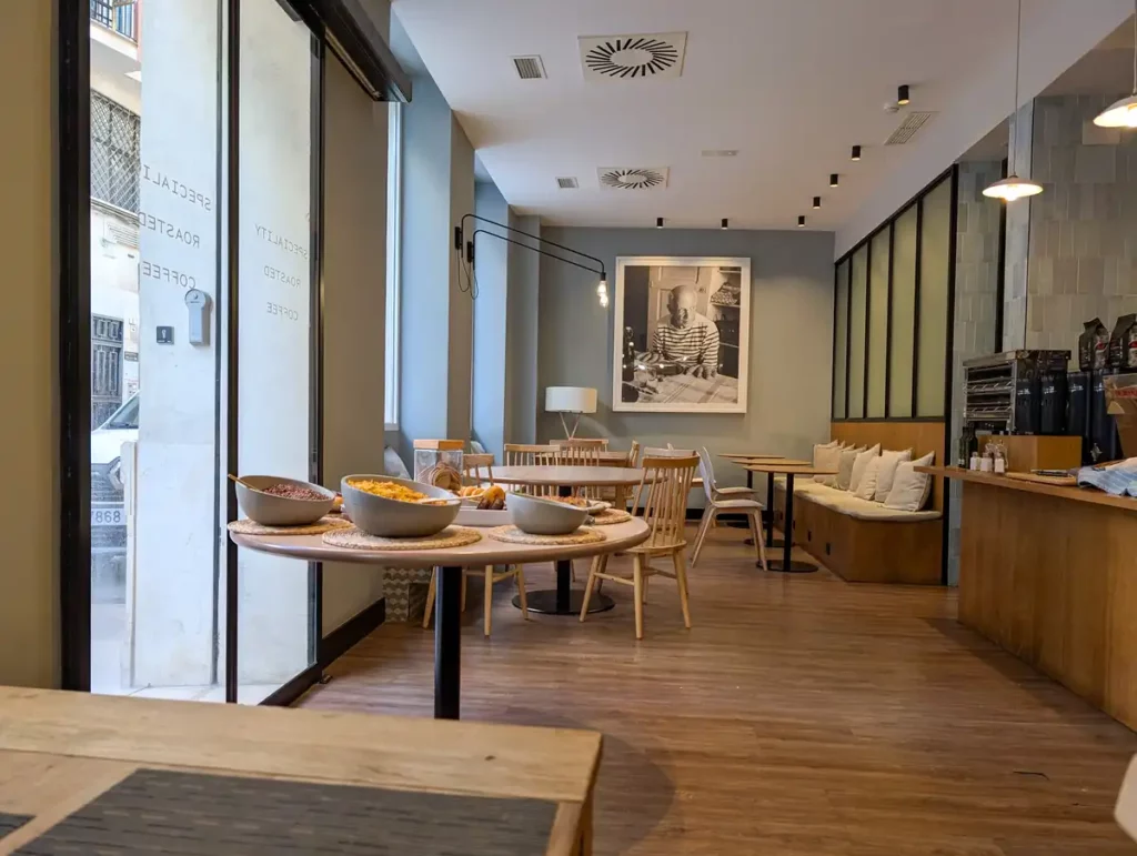 A coffee shop set up for breakfast, decorated in light wood and calming green tones