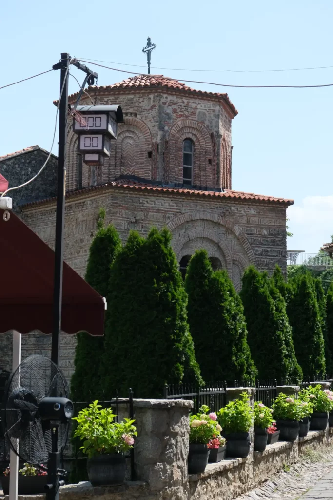 An old Byzantine church in Ohrid. There's a streetlamp in front of the church, and the lamp is in the shape of a three-storey black and white Ohrid house, with the storeys getting bigger as the house goes up, like an upside-down pyramid.