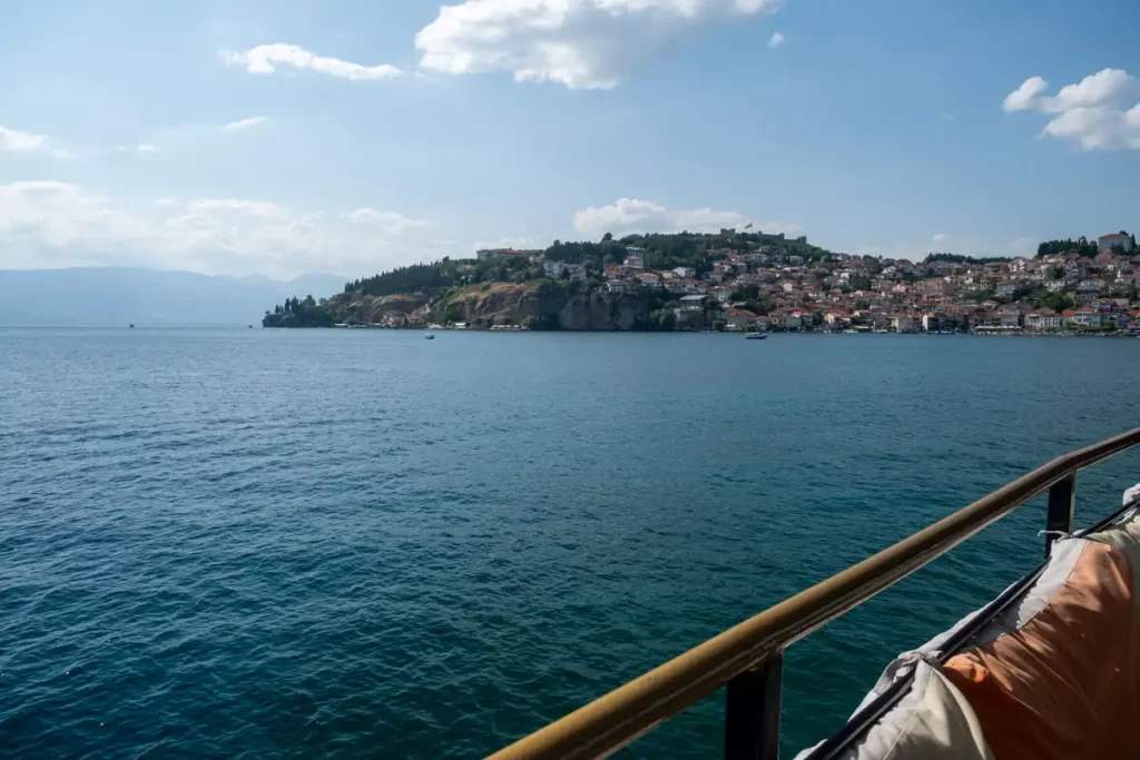 Looking back at Ohrid from a boat trip. The sky and the lake are beautifully blue, and you can just see the red roofs of the old town.