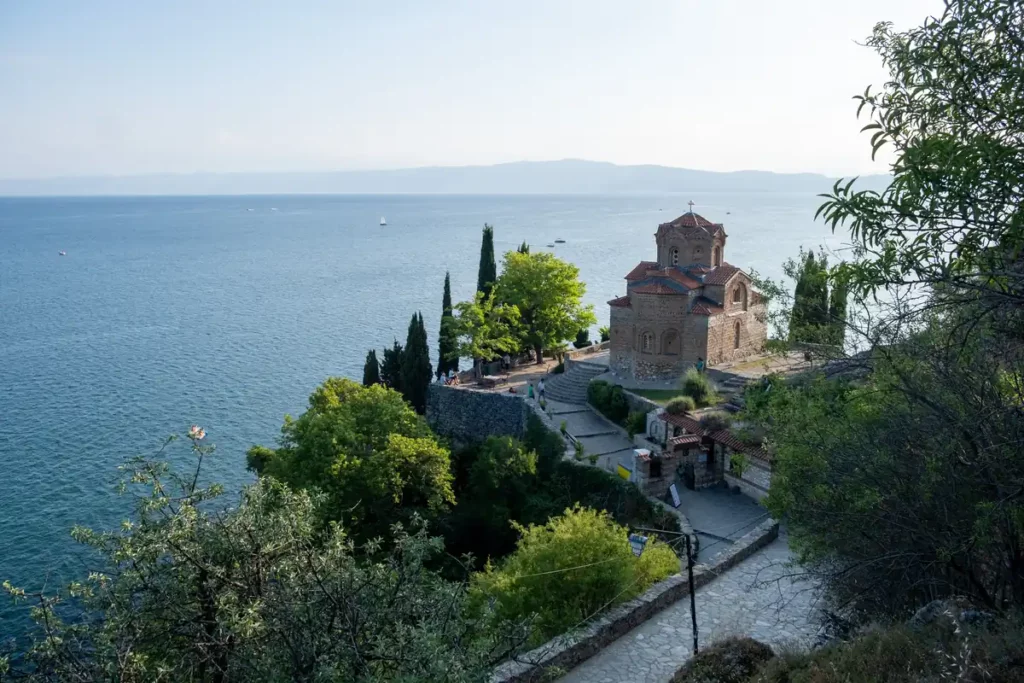 A beautiful brick built church on a cliff above a lake, surrounded by trees