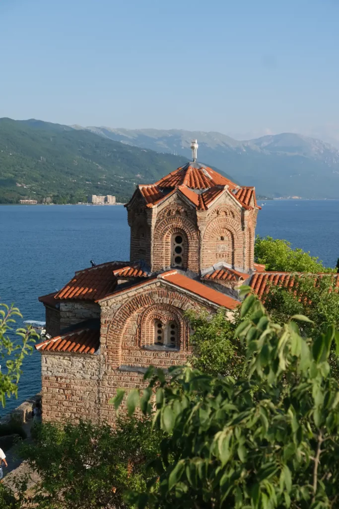A beautiful Byzantine church built in brick against the background of a lake and mountains