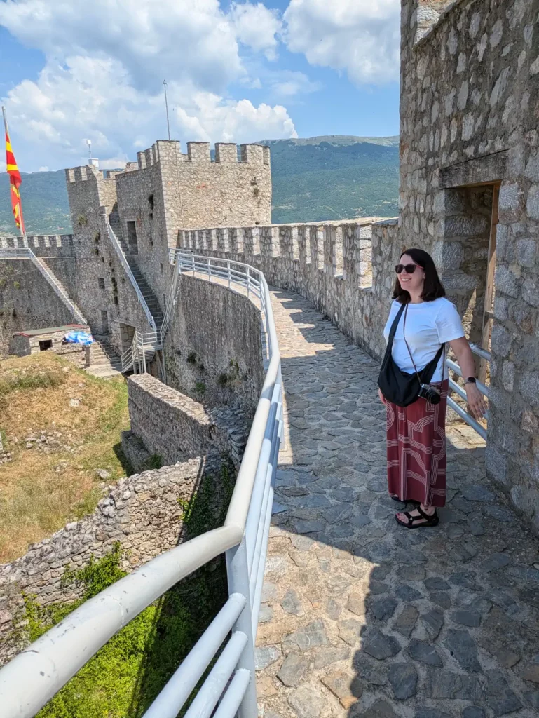 A woman with dark hair wearing summer clothes stood on a castle ramparts