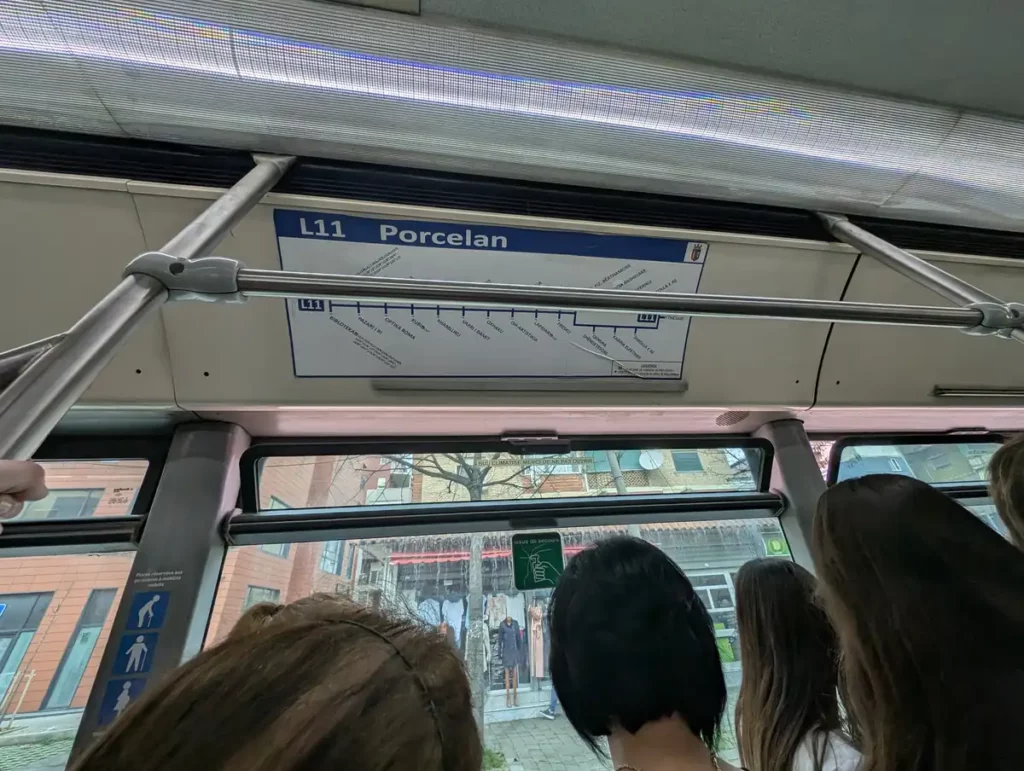 On the number 11 bus to Porcelan and Bunk'Art 1. People are stood holding on to the handrail. There's a bus map above the window showing the loop that the bus does at the end of the route. 
