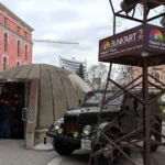 The entrance to Bunk'Art 2 in Tirana city centre. A concrete dome covers the entrance to the bunker museum. There's a military jeep and a surveillance tower to the side.