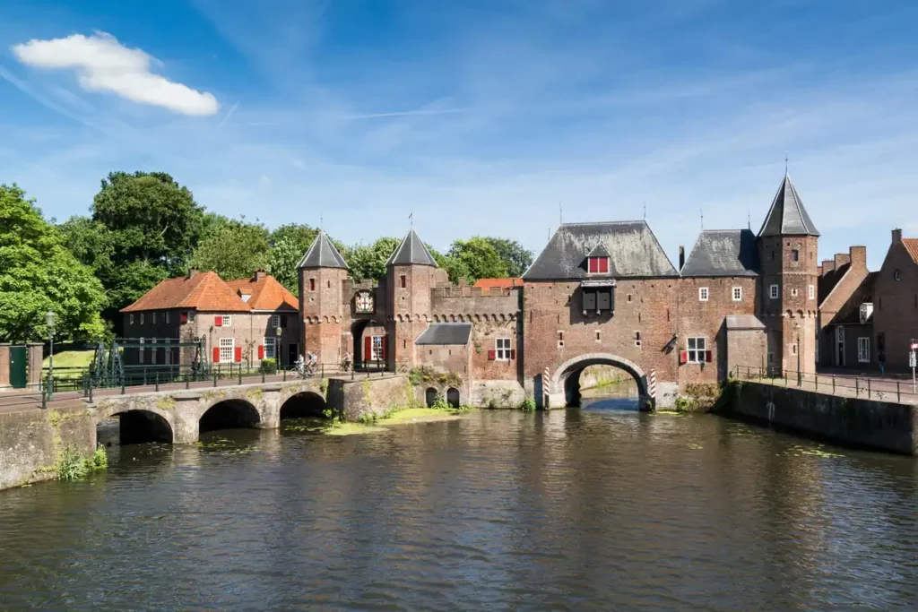 A wide medieval gate with turrets, spanning both a road and a waterway.