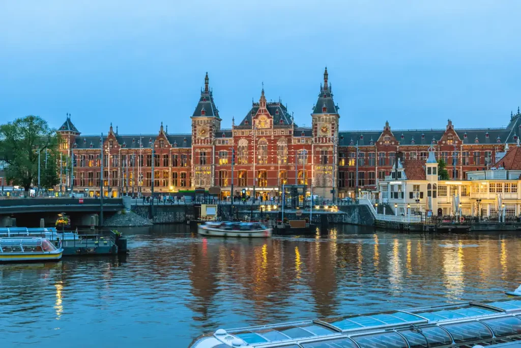 A large grand red brick building with a canal in front. 