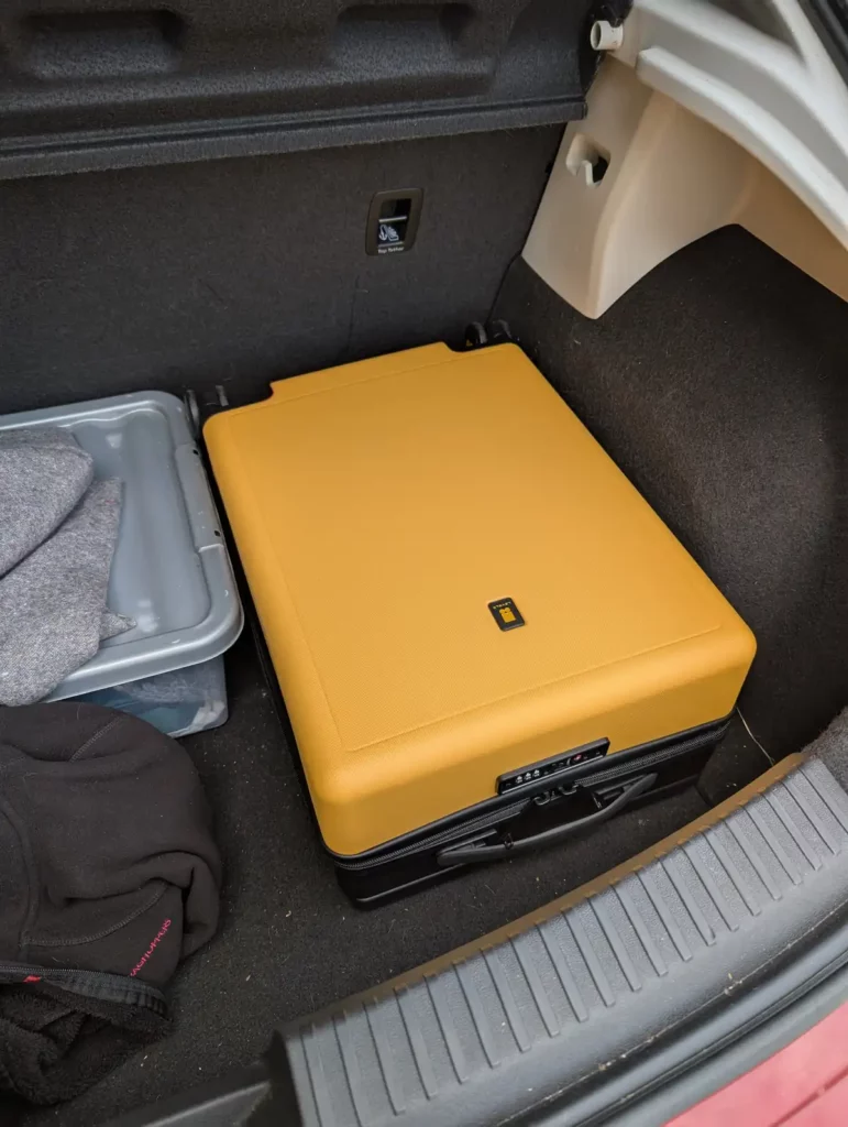 A yellow Level8 Voyageur 20" suitcase in a car boot with plenty of room to spare