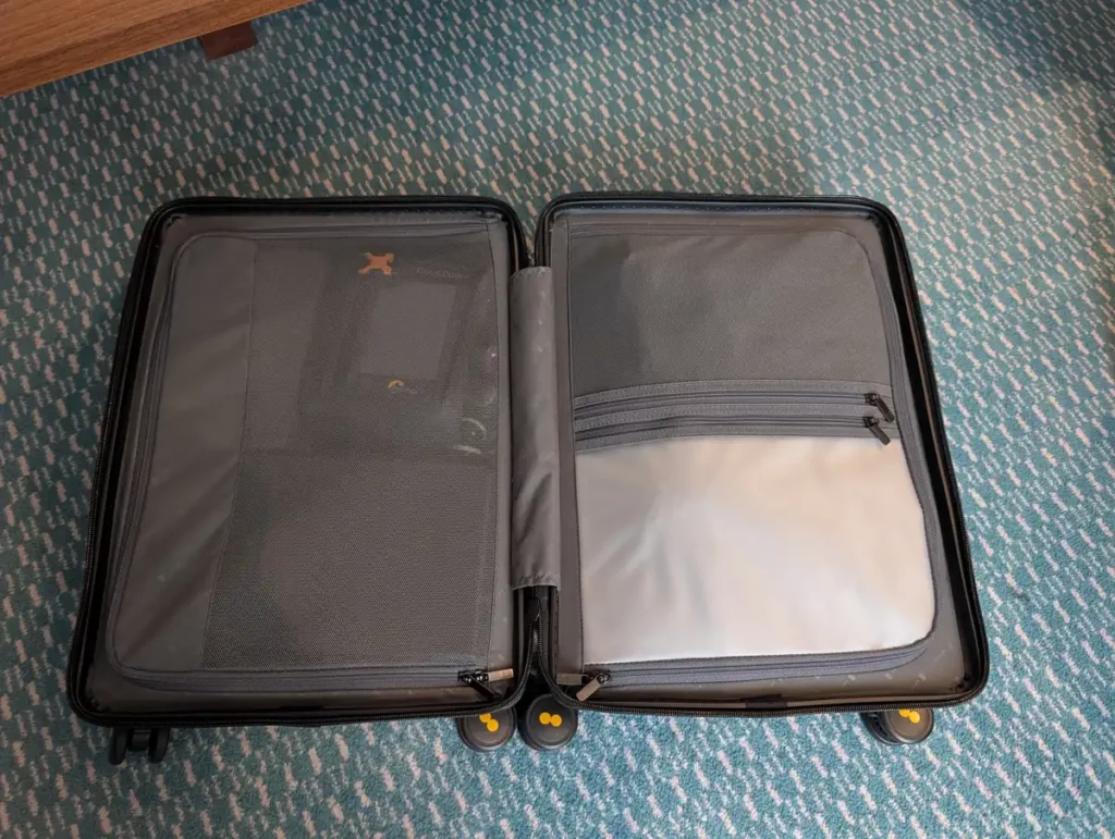 A suitcase open on the floor, showing the neat zip covers separating the compartments