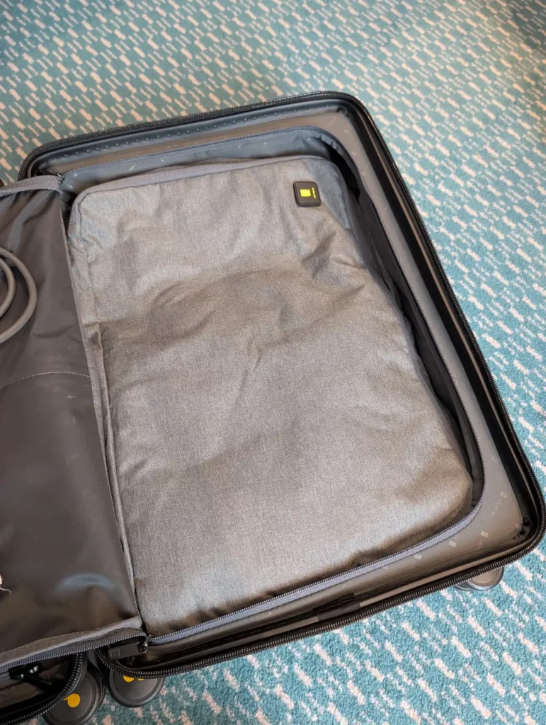 A suitcase with a large grey packing cube inside. The packing cube is a perfect fit for the case.