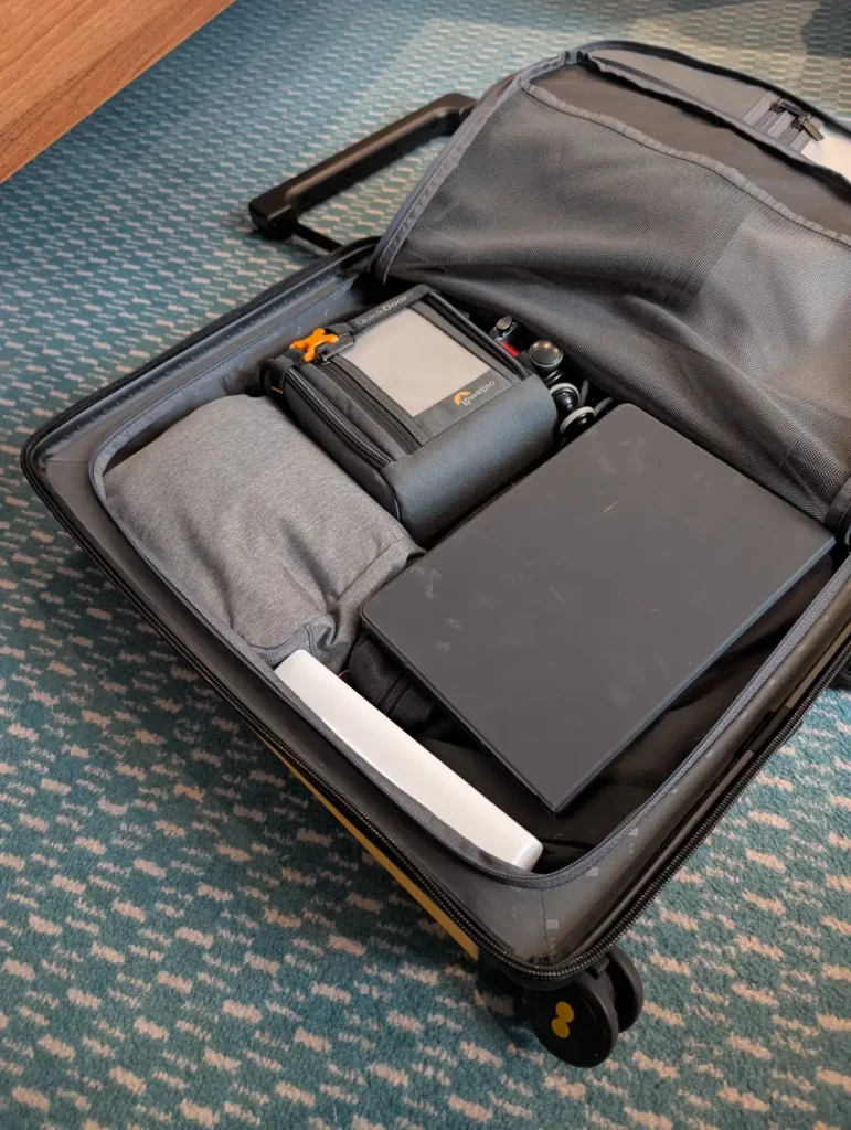 A suitcase packed with packing cubes and electronics
