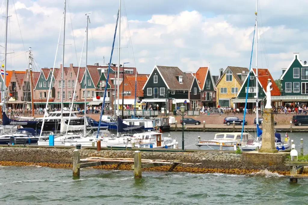 A busy harbour with lots of small boats and traditional wooden buildings painted in green and yellow.