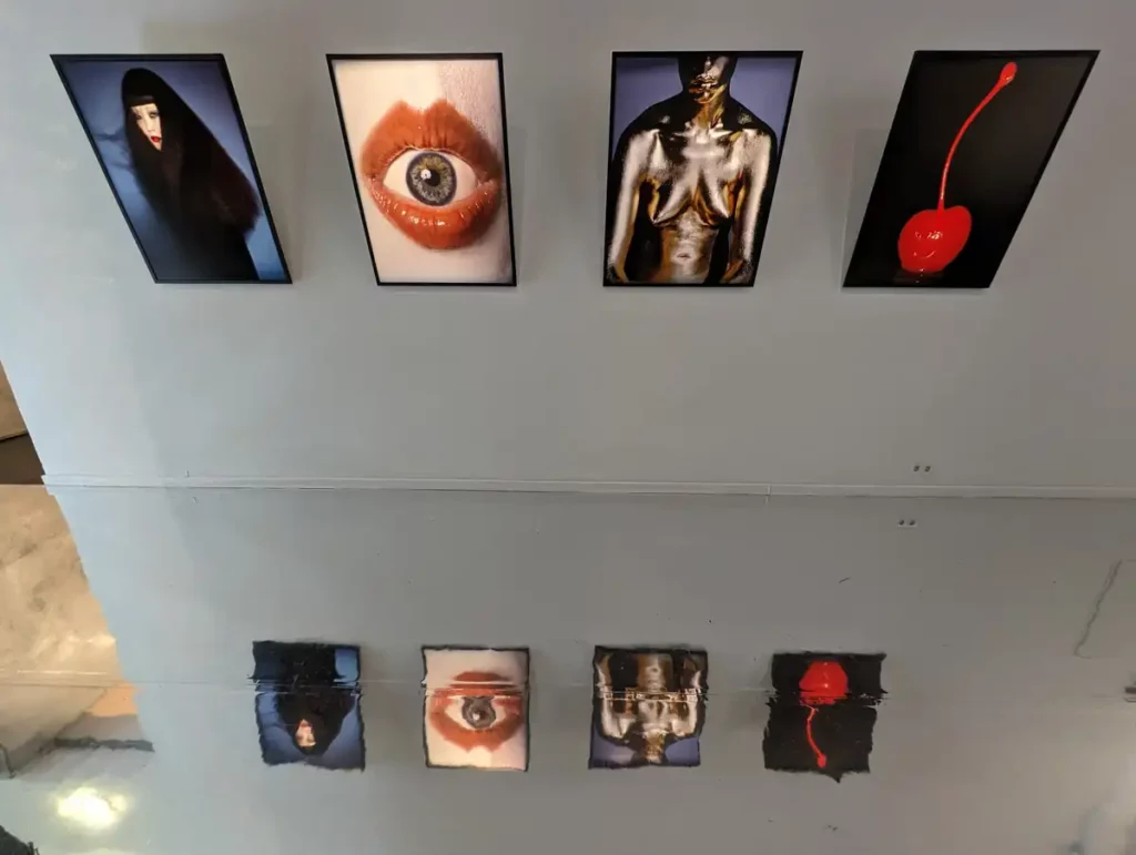 A photography exhibition with AI-augmented images of the human body in a gallery with a mirrored floor.