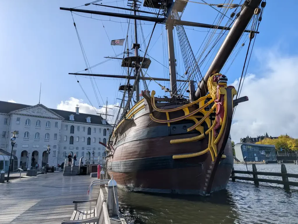 A wooden sailing ship in front of a grand old building