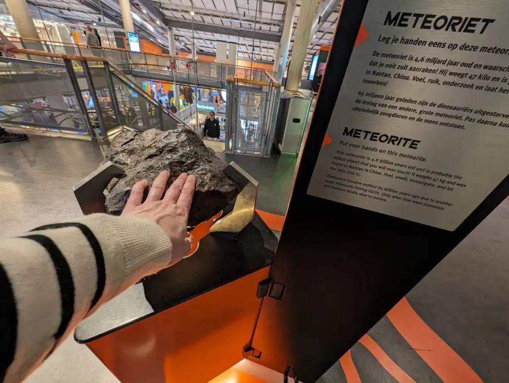 A woman's hand touching a meteorite inside the NEMO Science Museum, one of the best museums in Amsterdam