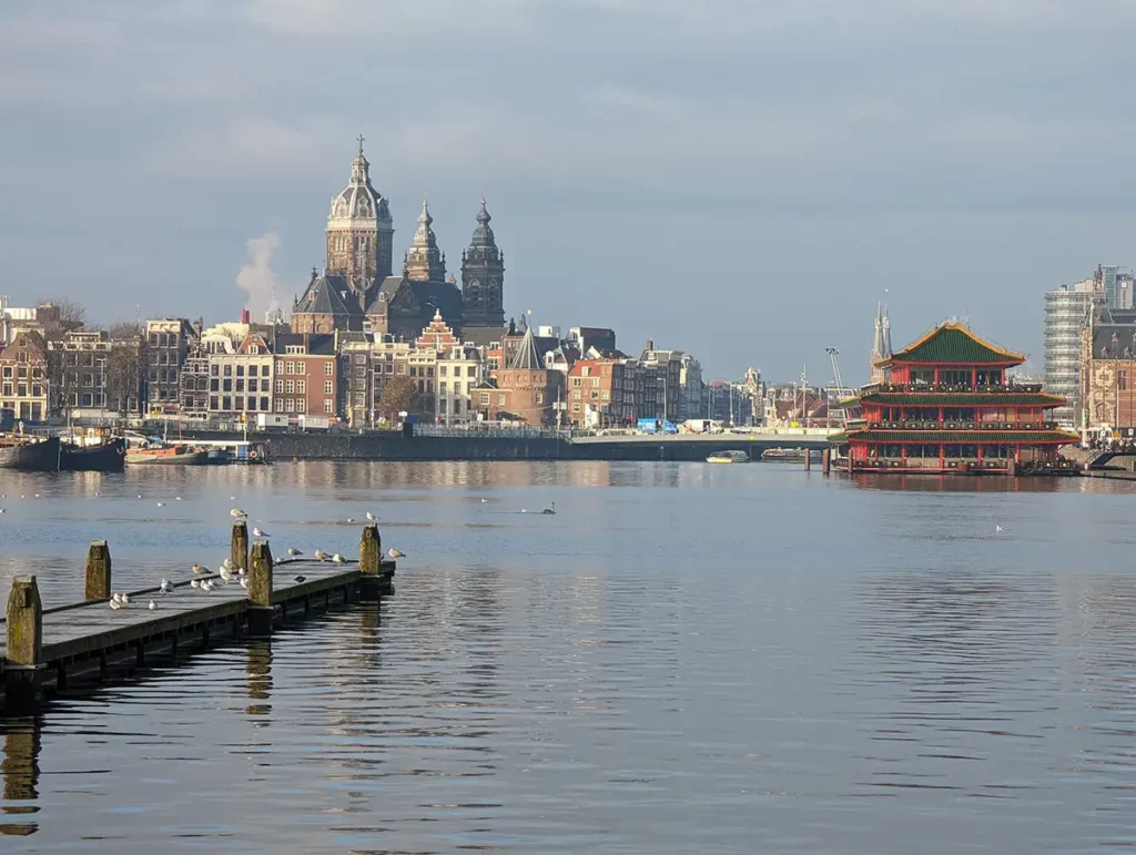 An expanse of water in Amsterdam city centre, with a floating Chinese restaurant on the right and a large church in the background