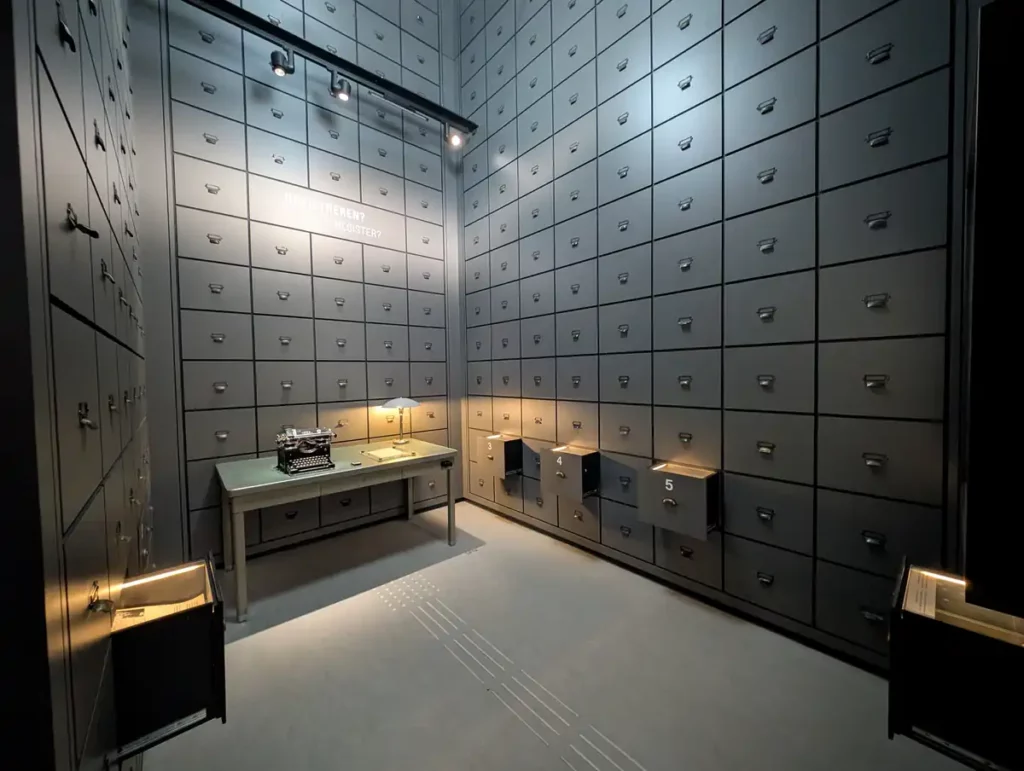 A room in the Dutch Resistance Museum. A desk is set up in a grey room, with rows and rows of drawers stretching up to the ceiling. The effect is very menacing. 