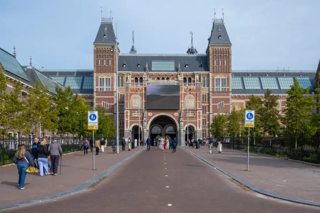 The outside of the Rikjsmuseum, one of the best museums in Amsterdam. A large and impressive old brick building with two towers sits across a busy cycle path.