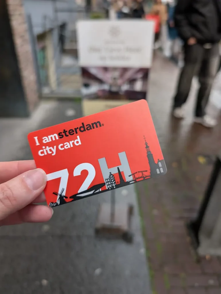 A hand holding an I amsterdam City Card in front of the Our Lord in the Attic hidden church museum in Amsterdam