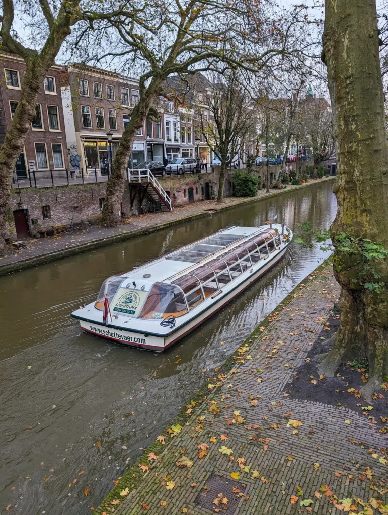A canal tour boat cruising along a canal in Utrecht