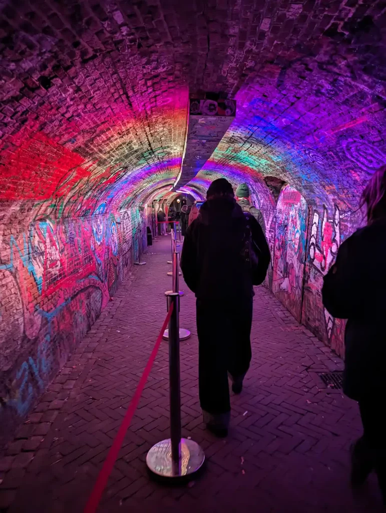 A stone tunnel, lit up with brightly coloured lights