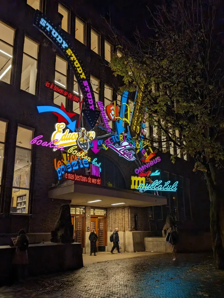 Brightly coloured words made out of lights above the entrance to a large building