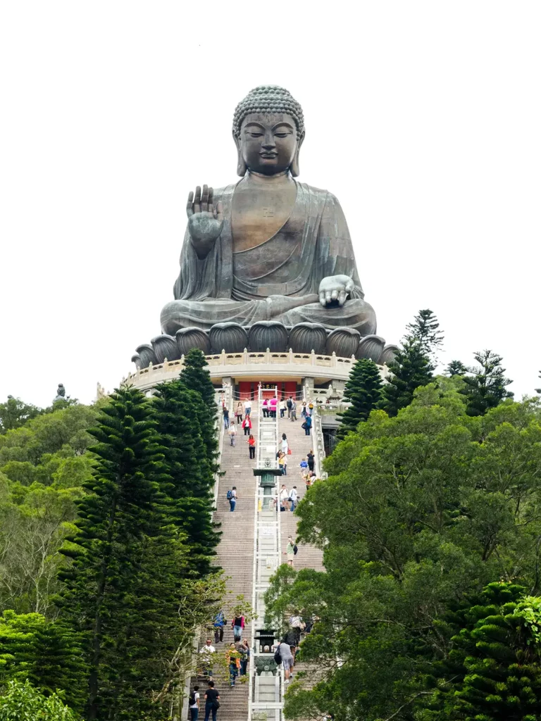 An enormous Buddha statue sitting at the top of a steep flight of stairs