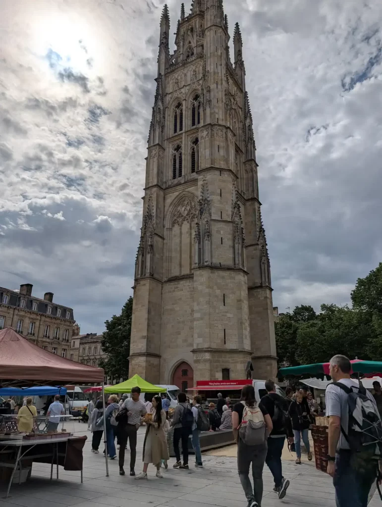 A farmers' market underneath a tall Gothic bell tower